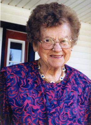 A woman with short brown hair wearing a purple patterned shirt.