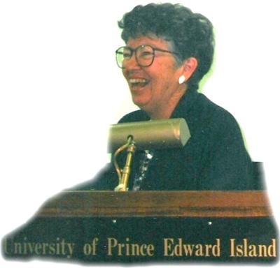 A laughing woman stands behind a podium at the University of Prince Edward Island.