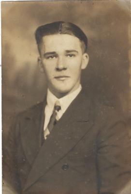 A sepia tinted photo of a young man wearing a jacket, shirt and tie. 