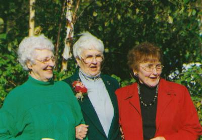 Three women standing arm in arm. 