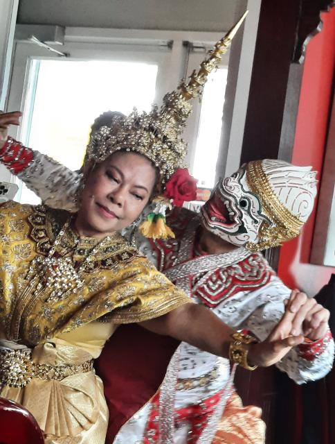 Two traditional Thai dancers in costumes, headdress, and mask.