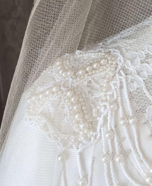 The beaded medallion on the replica wedding gown’s shoulder shown through the original veil at the Lucy Maud Montgomery Birthplace, New London, PEI.