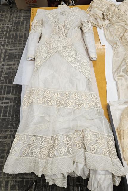 Ivory silk, lace, and voile wedding gown decorated with fabric roses and crossed lace bands belonging to Eleanor (Sharp) Long, circa 1910.